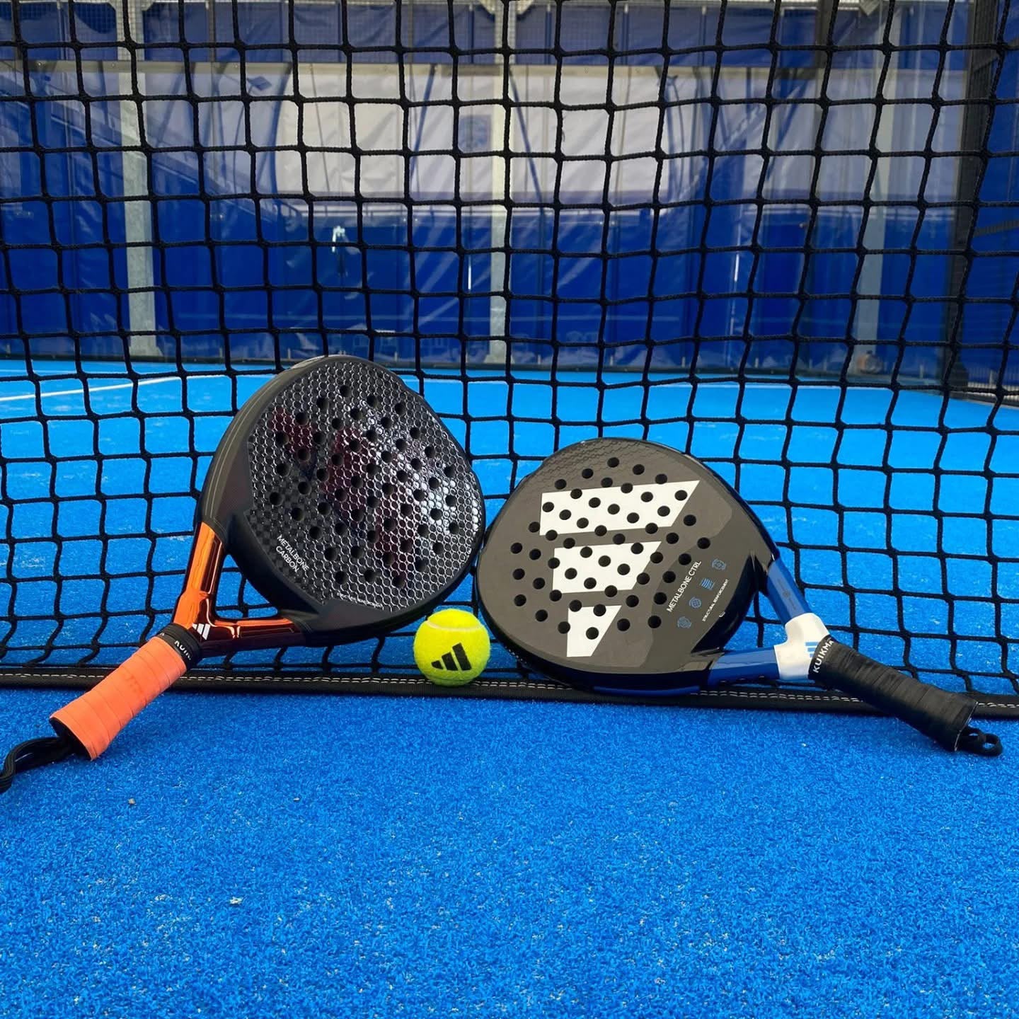 Due racchette da padel e pallina sul campo blu del Piroda Padel Club
